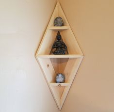 three wooden shelves with rocks on them in a corner next to a wall mounted buddha statue