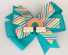 "**The size of the pictured bow is 5 inches,  but can be ordered in other sizes. Hair bows may be made with a french barrette or an alligator clip (as shown).  ITEM DETAILS *Ribbon Type: Base Layer- turquoise (If you'd like a different base color, leave me a comment.) Top Layer- diagonal stripes in pastel colors Embellishment center: polymer clay rainbow (rainbow clouds could slightly differ.) *BOW DIMENSIONS: 4\", 5\", or 6\" *CLASP: French Barrette, Alligator Clip, or nylon baby head band *Edges are heat sealed to prevent fraying *Assembled by hand using sewing and hot glue PRETTY PACKAGING** Gift Ready** Each purchase will be sealed in a clear cellophane bag with sparkly confetti and tied up with ribbon.  Ships from Charlotte, NC." Polymer Clay Rainbow, Clay Rainbow, Rainbow Clouds, Rainbow Bow, Pastel Stripes, Rainbow Cloud, Packaging Gift, French Barrette, Pretty Packaging