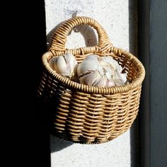 a wicker basket hanging on the side of a building with garlic in it,