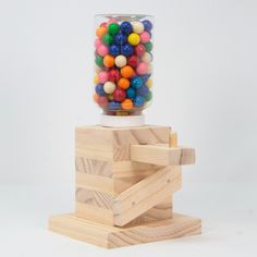 a gummy ball machine is on top of a wooden block and it's full of colorful balls