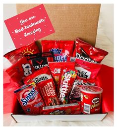 a box filled with snacks and candy on top of a red cloth covered tablecloth