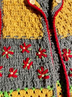 there is a crocheted jacket with red flowers on the front and yellow sleeves