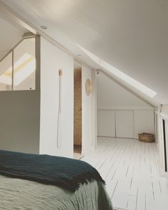 an attic bedroom with wooden floors and white walls