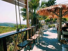 people are sitting at tables with umbrellas and chairs on the deck overlooking the ocean