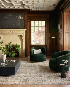 a living room with two green chairs and a coffee table in front of a fireplace