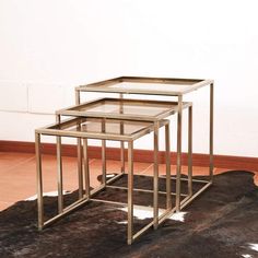 three metal and glass tables sitting on top of a cowhide rug