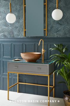 a bathroom with blue walls, gold fixtures and a large mirror on the wall above it