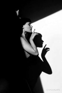 black and white photograph of a woman with her shadow on the wall