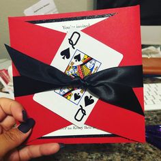 a hand holding up a card that has playing cards on it with a black bow