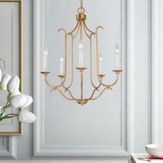 a chandelier hanging from the ceiling in a room with white flowers and framed pictures