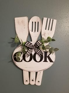 a wooden sign that says cook with utensils and greenery on the front