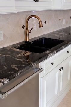 a kitchen with marble counter tops and stainless steel dishwasher in the center, along with white cabinets