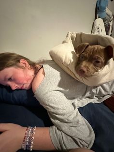 a woman laying on top of a bed with a dog wrapped around her neck and head