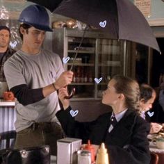 a man holding an umbrella over a woman at a table with other people in the background