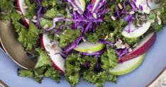 a blue bowl filled with greens and apples