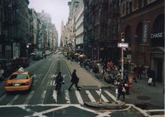 people are crossing the street at an intersection in new york city, with cars and pedestrians