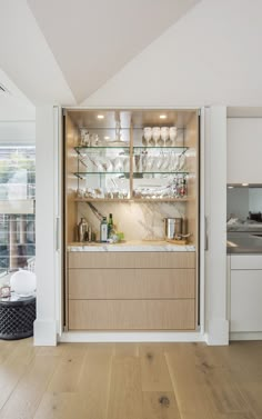 a kitchen with wooden flooring and cabinets filled with glassware on top of shelves