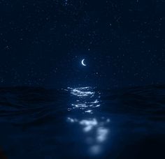 the moon shines brightly in the night sky over the ocean with dark blue water