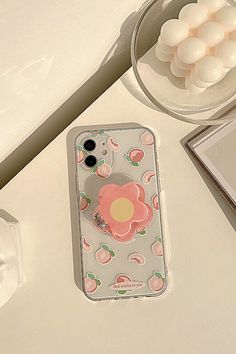 an iphone case with a flower on it sitting next to a bowl of marshmallows