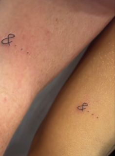 two people with tattoos on their legs, one has an arrow and the other has a cross