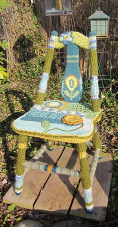 a crocheted chair sitting on top of a wooden deck