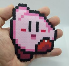 a hand holding a small pink and black pixellated object in it's palm