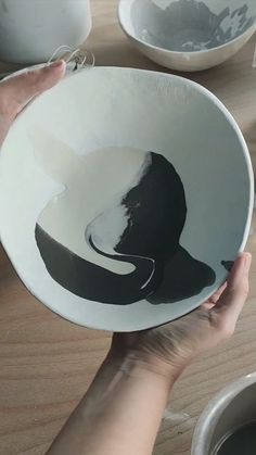 a person holding a white bowl with a black design on it