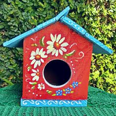 a red birdhouse with flowers painted on it