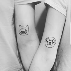 two people with matching tattoos on their arms, one has a dog and the other has a cat