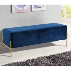 a blue bench sitting on top of a rug in front of a wall mounted painting