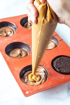 a person dipping something into a cupcake in a muffin tin with chocolate and caramel