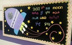 a bulletin board with an image of a rocket ship and the words shoot for the moon on it