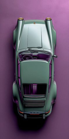 an overhead view of a green sports car on a purple background with gold rims