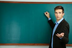 a man standing in front of a blackboard pointing to something on the chalk board