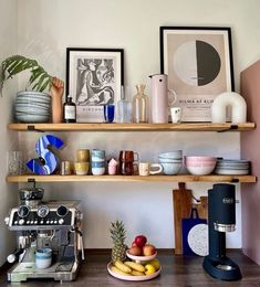 a kitchen shelf filled with plates, cups and other items next to an espresso machine