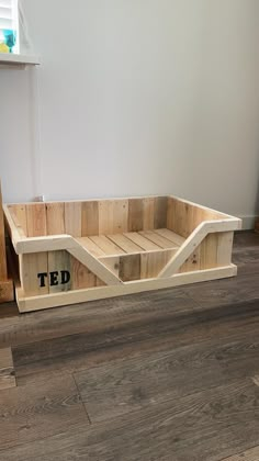 a wooden crate sitting on top of a hard wood floor next to a white wall