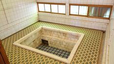 an empty room with tiled walls and flooring in the center is seen from above