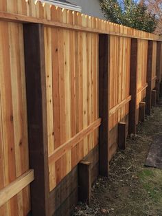 a wooden fence is lined up against the side of a house with grass in front of it