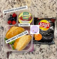 two plastic containers filled with food on top of a marble countertop next to a bag of chips