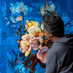 a man standing in front of a painting with flowers on it