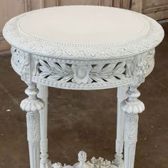 a white table with ornate carvings on the top and bottom, sitting in front of a door