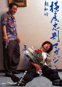 two men standing next to each other with flowers in front of them on the ground