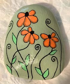 a painted rock with orange flowers on it