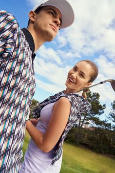 a man standing next to a woman holding a golf club