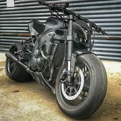 a black motorcycle parked in front of a garage door with no one on it's bike