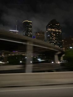 the city skyline is lit up at night as seen from an overpass in this blurry photo