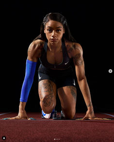 a woman with tattoos on her arms and legs crouching down while holding a tennis racquet