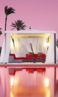 an outdoor pool with a canopy bed and red couches