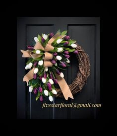 a wreath with purple and white tulips hanging on a door