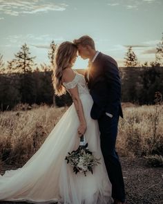 a bride and groom kissing in front of the sun